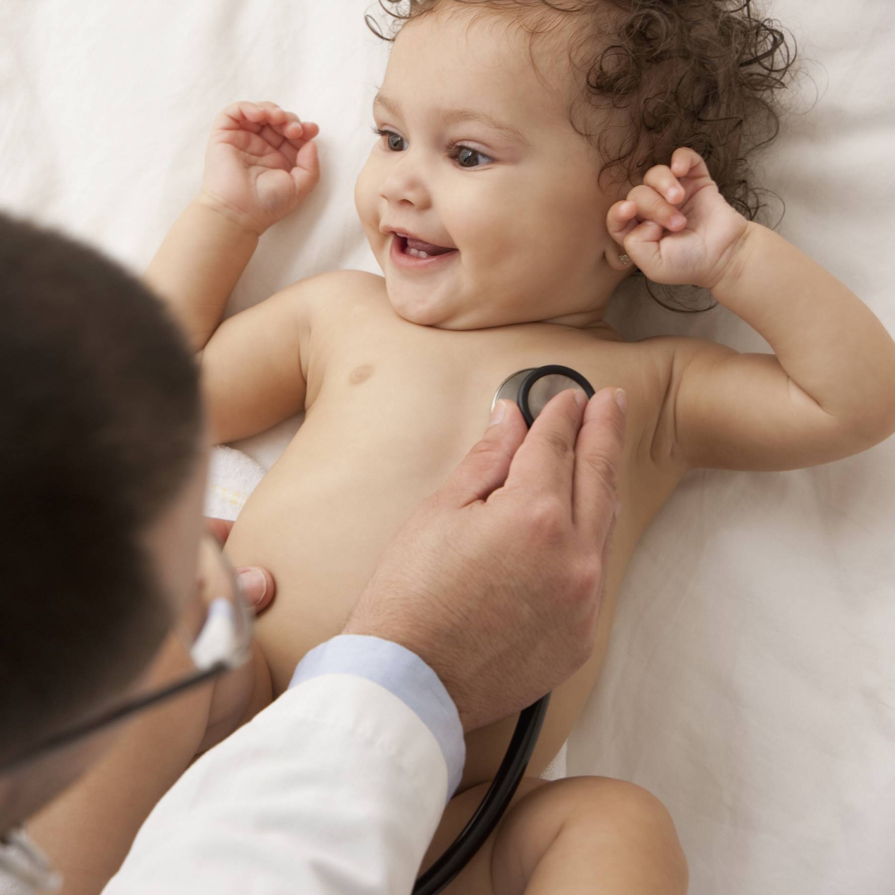 Healthcare provider using stethescope to listen to infant's heart beat