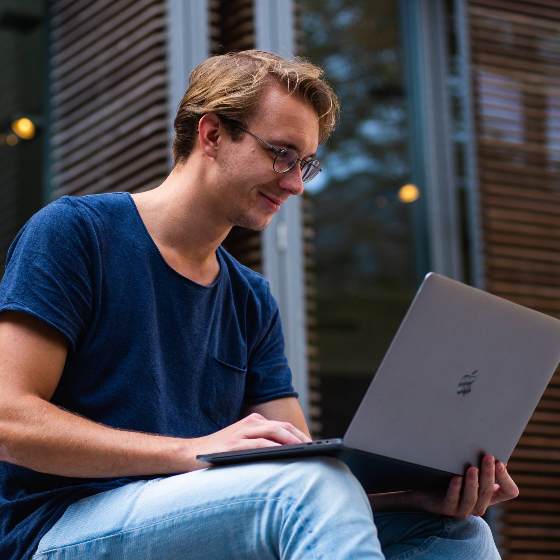 Smiling young man reading on his laptop.